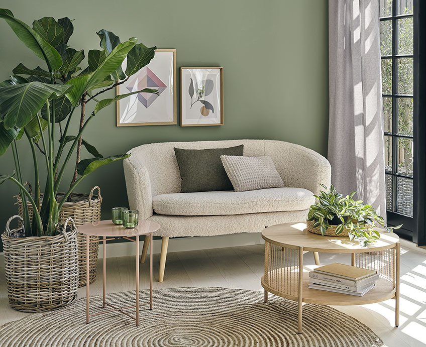 Vardagsrum med en vit soffa, soffbord i ek och gröna växter